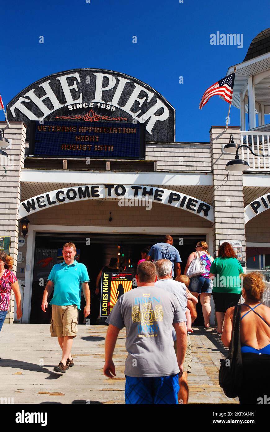 An einem Sommertag betreten und verlassen Besucher den historischen Pier am Old Orchard Beach in Maine Stockfoto