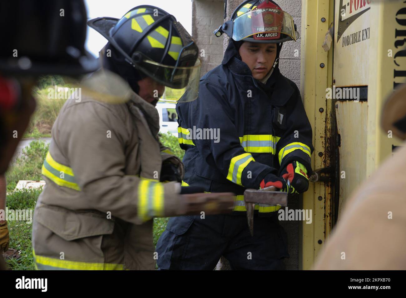 Feuerwehrleute üben beim gemeinsamen Training auf der Marine Corps Base (MCB) Camp Blaz, Guam, 4. November 2022, eine Tür zu durchbrechen. Die Schulung umfasste Feuerwehrleute aus dem MCB Camp Blaz, dem Marinestützpunkt Guam, dem Luftwaffenstützpunkt Andersen und der Feuerwehr von Guam. Durch die Schulung wurde die Fähigkeit des inselweiten Teams gestärkt, auf zukünftige Brand- und Rettungsnotfälle zu reagieren. Ziel dieser Schulung war es, Feuerwehrleute aus allen Diensten und der Guam Feuerwehr durch verschiedene Module zu Schulen, die Folgendes beinhalteten: Erdleitertaktik, Opferbeseitigung, Luftleitervertrauen, gewaltsames Eindringen, Notfall Stockfoto