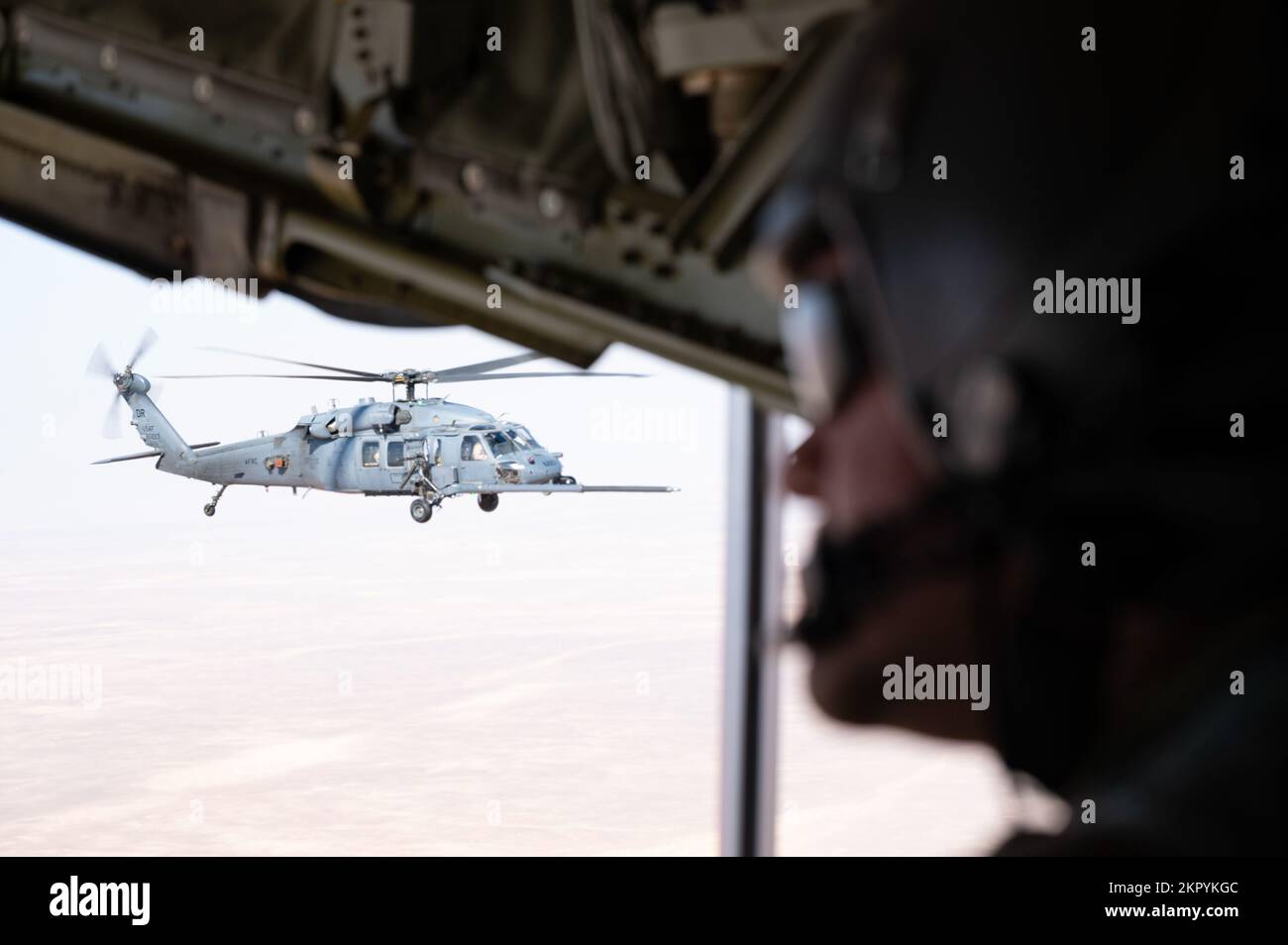 EIN US-AMERIKANISCHER Air Force Tech. Sgt. Michael Gesford, 26. Expeditionary Rescue Squadron HC-130J Combat King II Loadmaster, beobachtet, wie ein HH-60G Pave Hawk während einer Hubschraubermission mit Air-to-Air-Betankung (HAAR) in den USA Kraftstoff von einem HC-130J Combat King II erhält Zuständigkeitsbereich des Zentralkommandos, 4. November 2022. Die Hauptaufgabe des Pave Hawk ist es, Tag und Nacht in feindseligen Umgebungen Bergungsoperationen durchzuführen, um isoliertes Personal während eines Konflikts zu Bergen. HAAR Operations fungiert als Kraftausweiser und hält Rettungskräfte länger in der Luft. Stockfoto