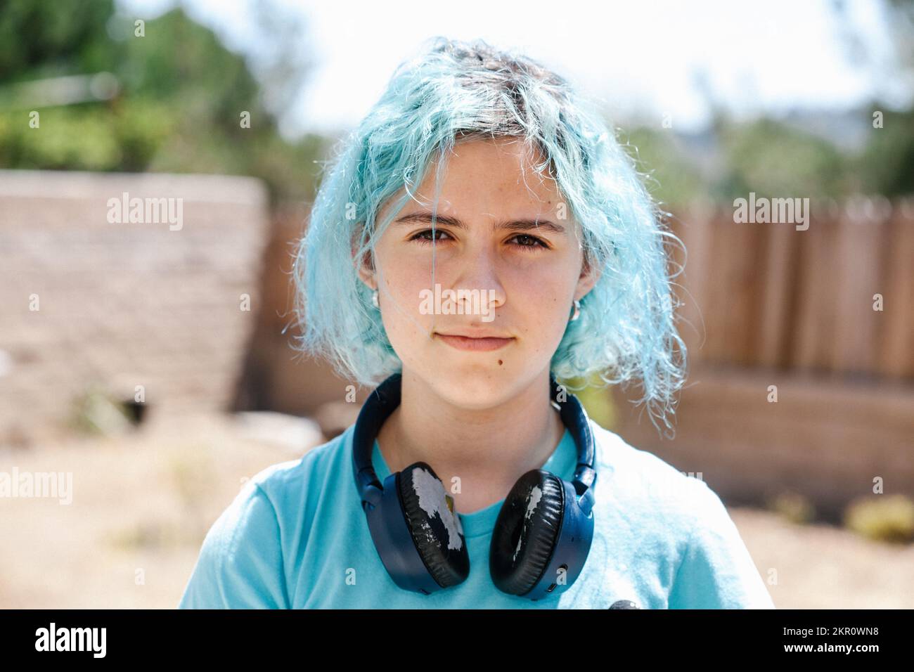 Teenager-Mädchen mit blauem Haar an einem sonnigen Tag mit Wornout-Kopfhörern Stockfoto