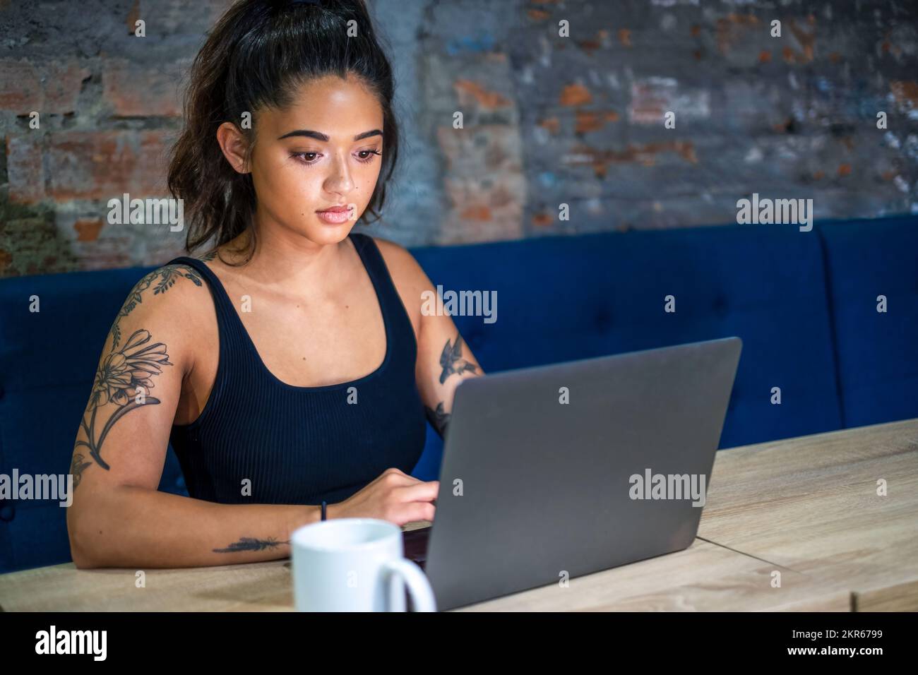 Weibliche digitale Nomadin, die an einem Laptop in einem modernen Gemeinschaftsarbeitsplatz arbeitet Stockfoto
