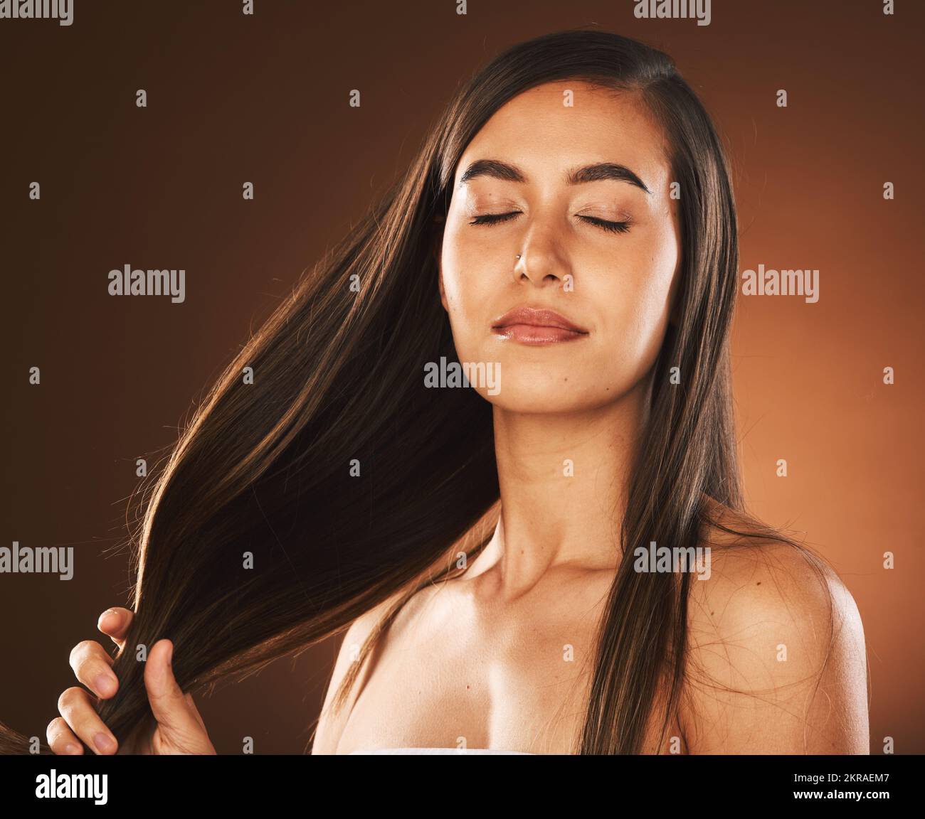 Gesichts-, Schönheits- und Haarpflege bei Frauen mit geschlossenen Augen im Studio isoliert auf braunem Hintergrund. Hautpflege, Make-up und Kosmetik des gesunden weiblichen Modells Stockfoto