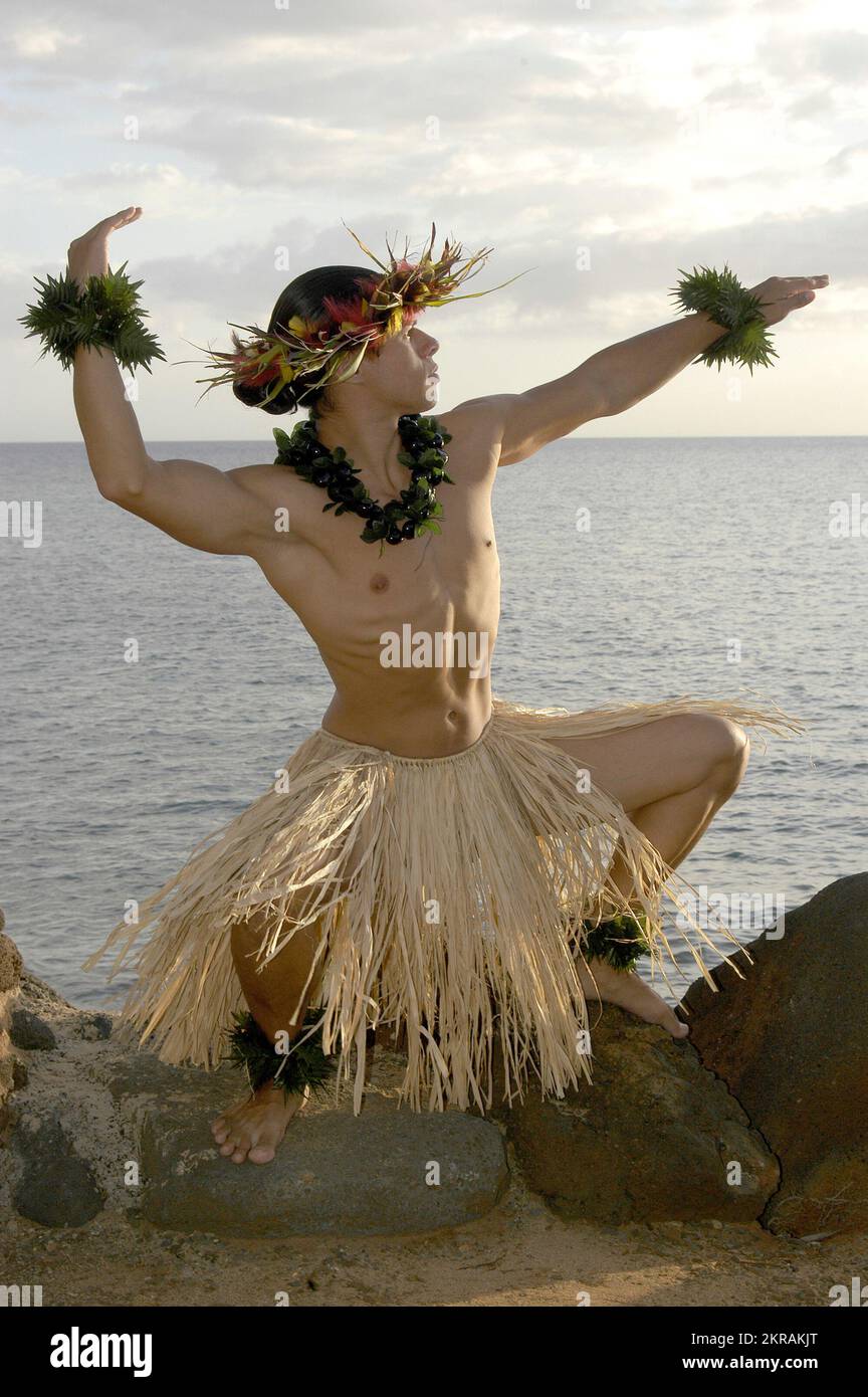 Der männliche Hula-Tänzer posiert am Strand in einer traditionellen Sonnenanbetungsbewegung. Stockfoto