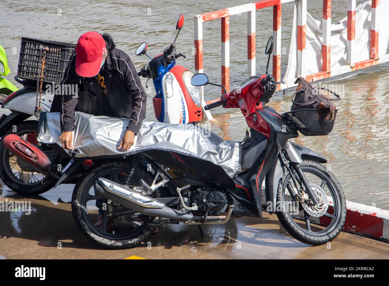 Ein Motorradfahrer parkt sein Motorrad an einer überfluteten Straße, Thailand Stockfoto