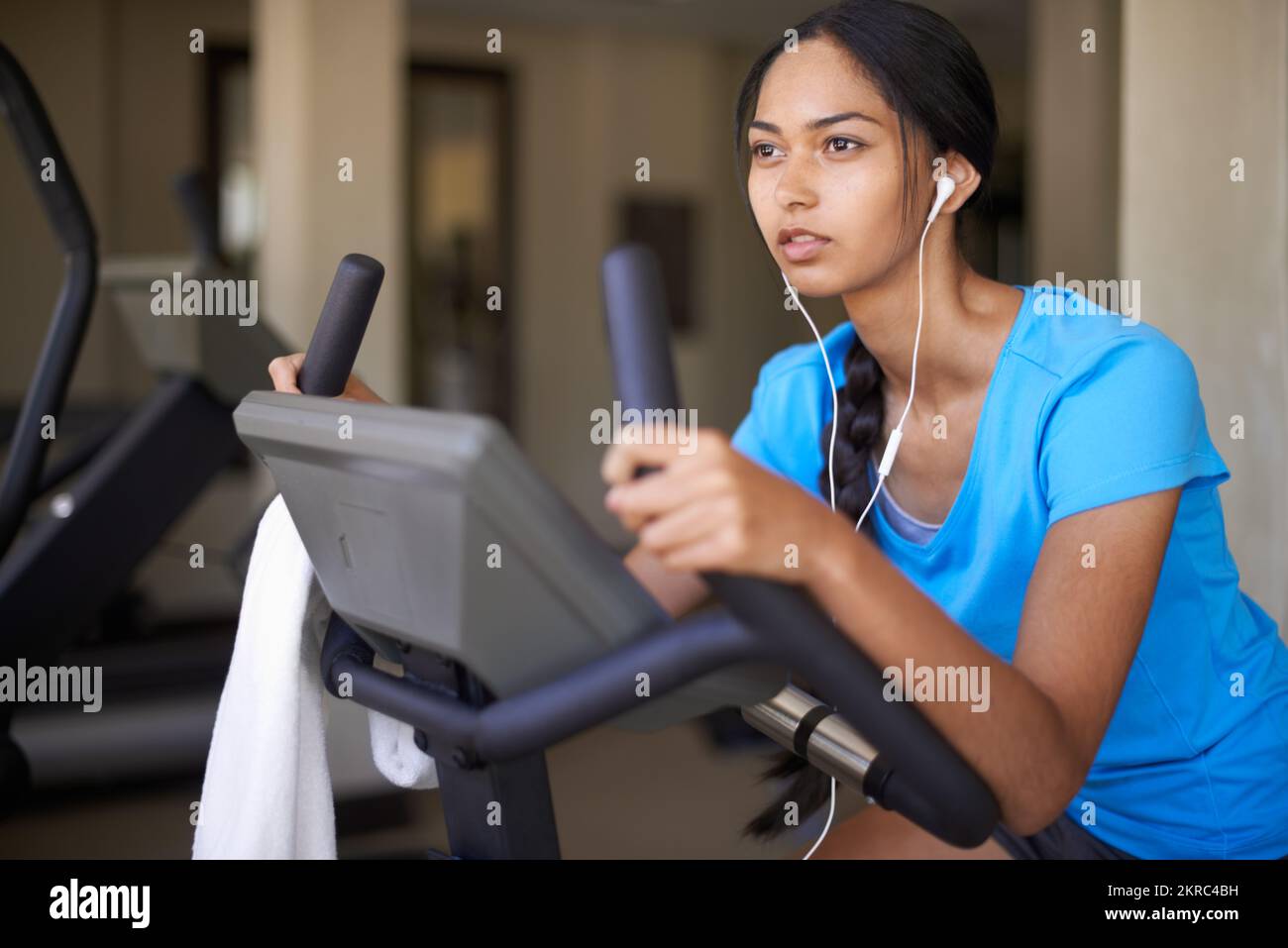 Ganzkörpertraining. Eine junge ethnische Frau, die im Fitnessstudio auf einem Heimtrainer trainiert. Stockfoto
