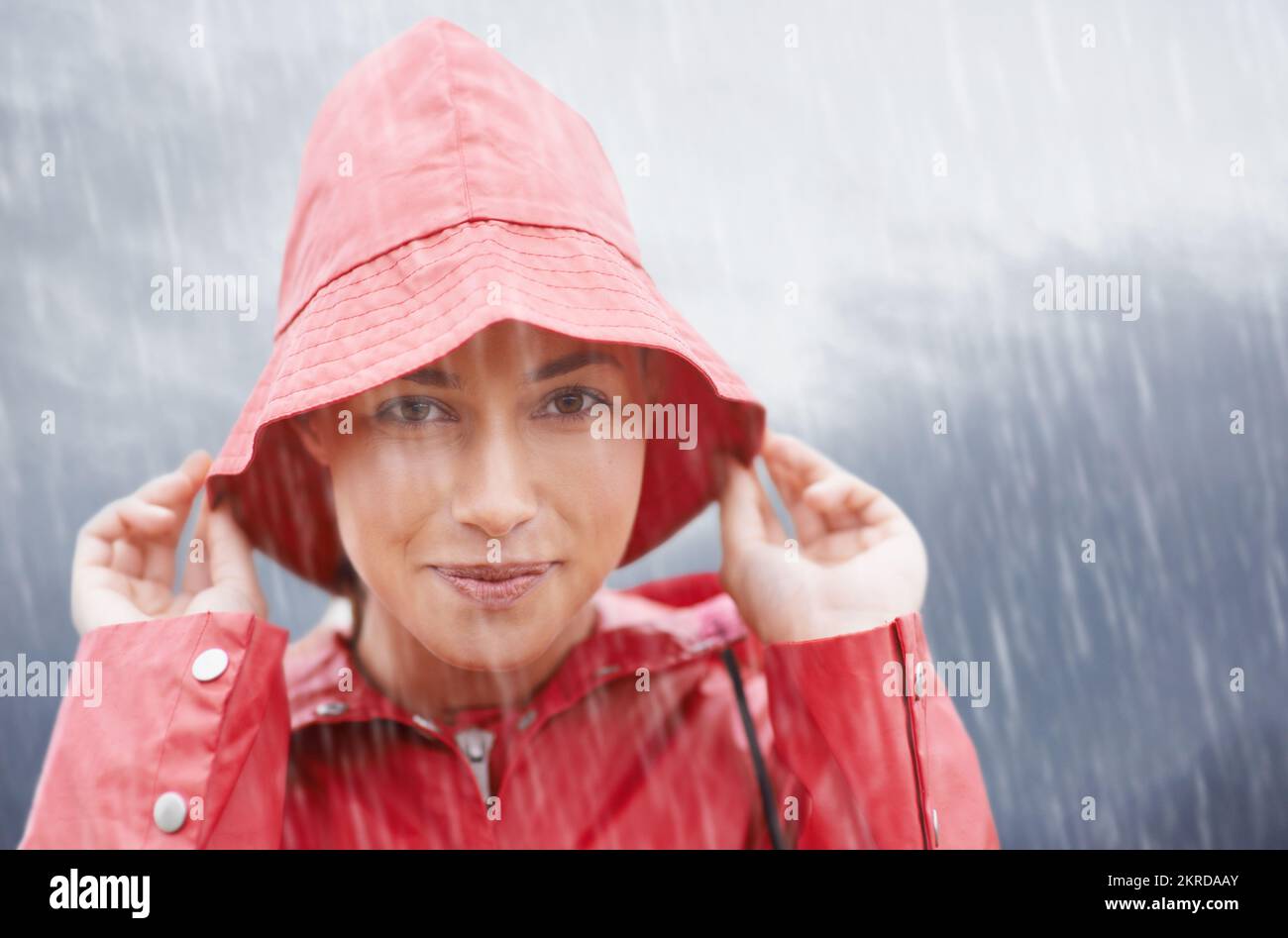 Regen... aber ich bin gedeckt. Eine attraktive junge Frau, die im Regen steht. Stockfoto