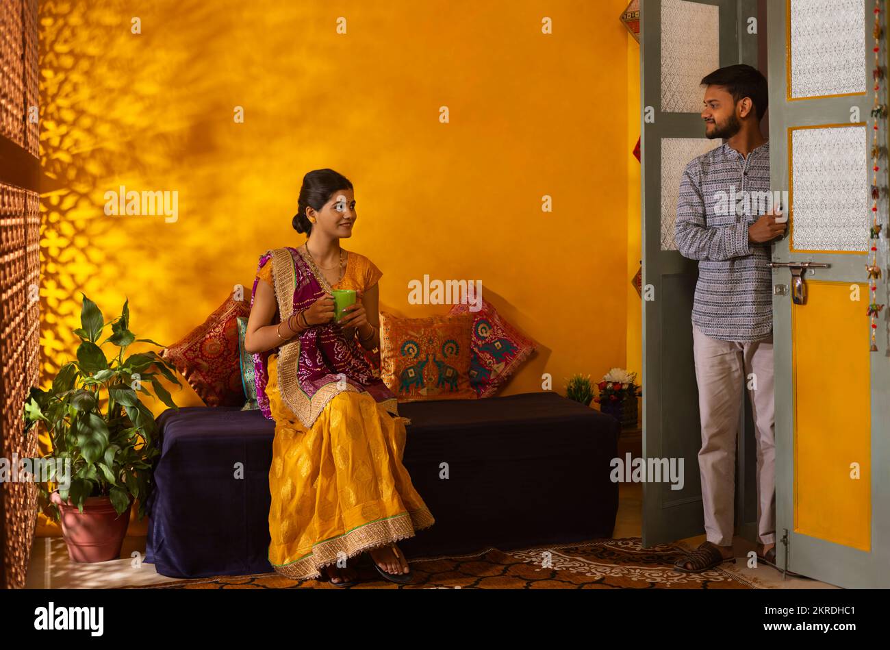 Gujarati mit einer Tasse Kaffee, die mit ihrem Mann vor der Tür spricht Stockfoto