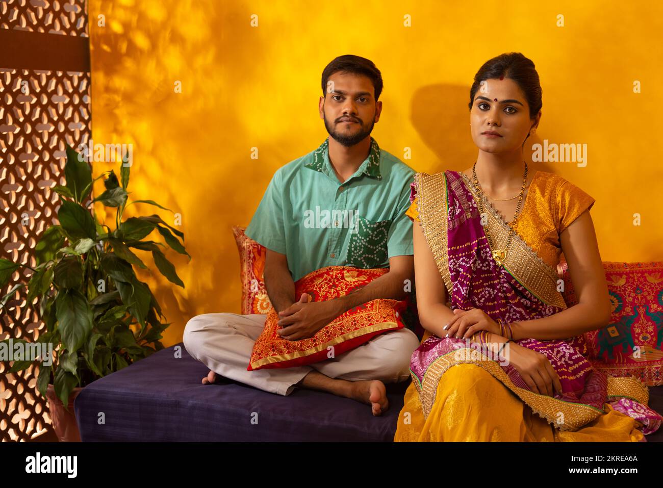 Portrait eines lächelnden Gujarati-Paares, das zu Hause auf Deewan sitzt Stockfoto
