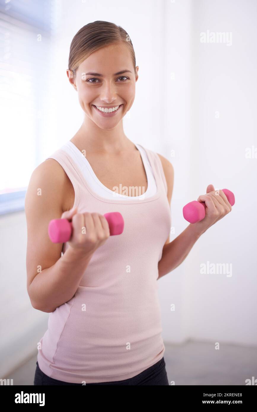 Sie ist motiviert, gesund und fit zu bleiben. Eine schöne junge Frau, die mit Gewichten trainiert. Stockfoto