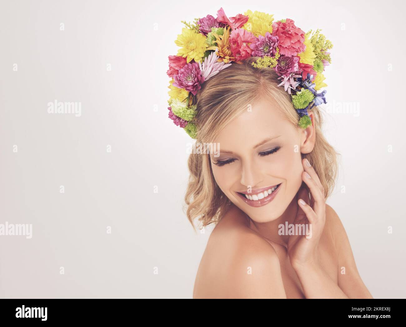 Ihre Schönheit ist wahr. Eine junge Frau posiert mit geschlossenen Augen und Blumen im Haar. Stockfoto