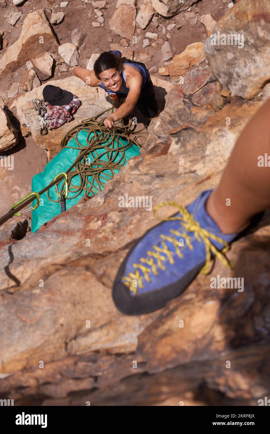 Felskletterer leben am Rande. Eine Klettererin, die am Rand eines Felsgesichts steht, während ihr Hinterwäldler unten steht. Stockfoto