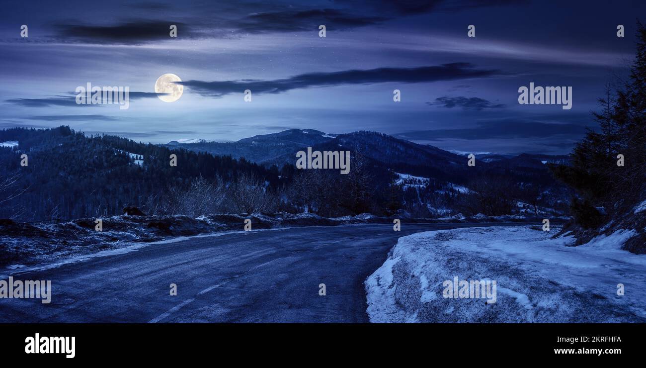 Der uzhanische Pass im Winter bei Nacht. Alte Landstraße durch die Berge. Wunderschöne Landschaft mit bewaldeten Hügeln im Vollmondlicht Stockfoto