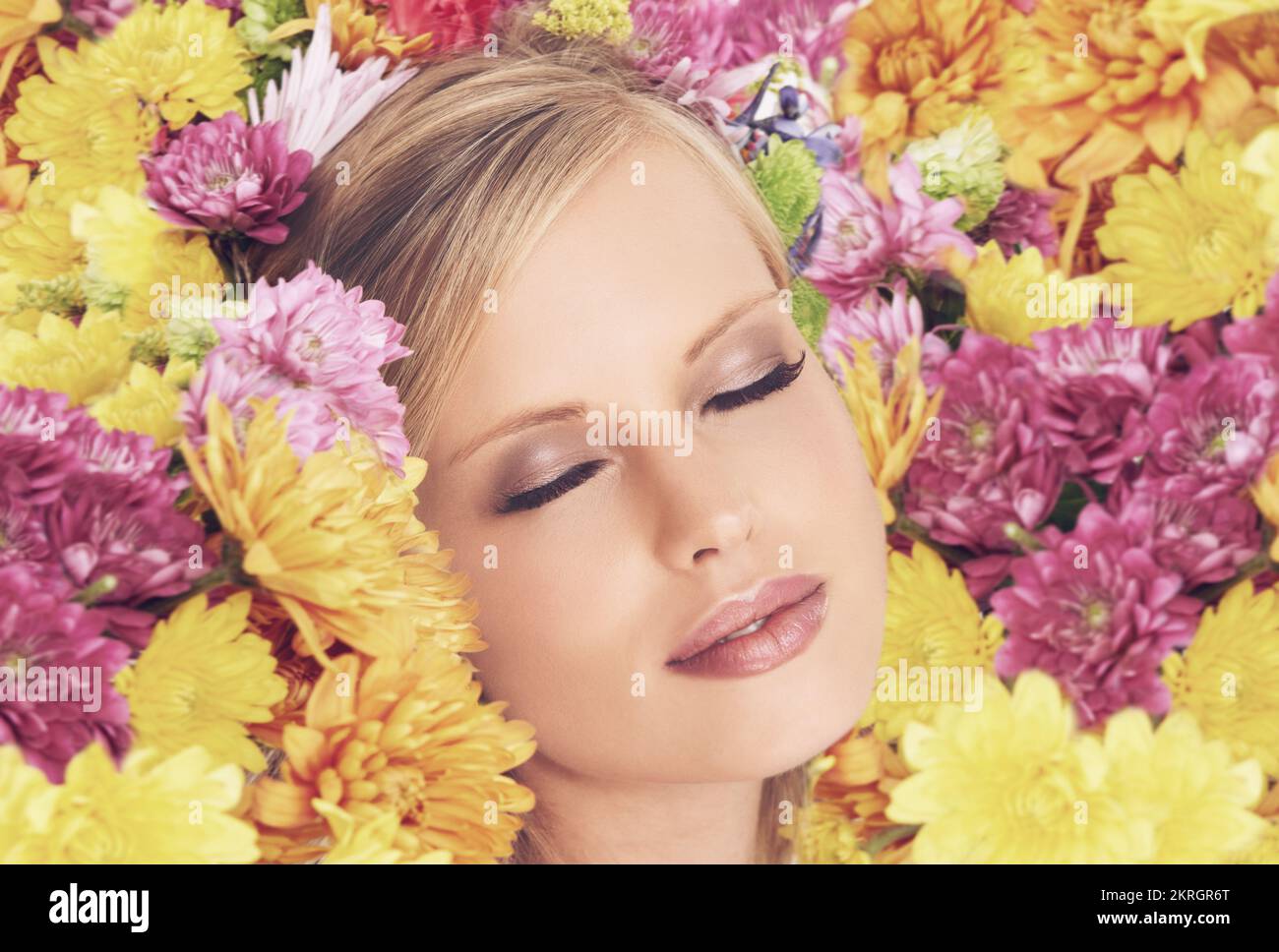 Ich fühle mich blumig. Eine junge Frau posiert mit geschlossenen Augen und Blumen im Haar. Stockfoto