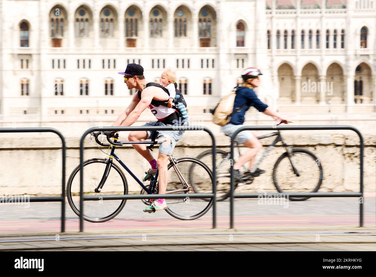 Ein Fahrradfahrer, der das Baby hinten in der Stadt trägt Stockfoto