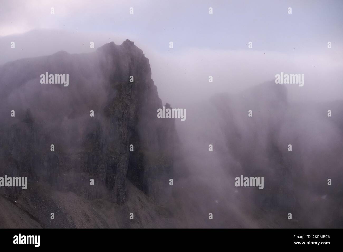 Atemberaubende hohe Klippen von felsigen Bergen in nebligen Wolken in den East Fjords von Island Stockfoto