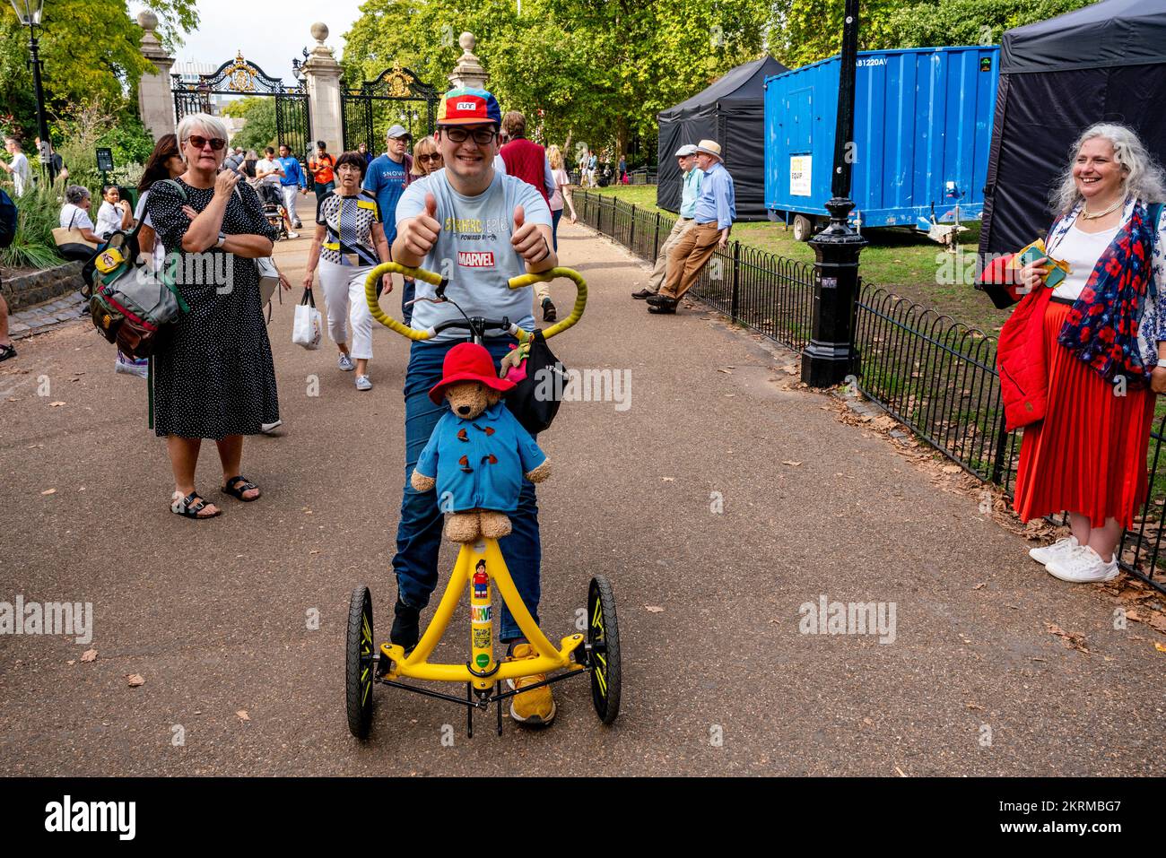 Ein junger Mann, der mit Einem großen Paddington-Bär im St. James's Park nach dem Tod von Königin Elizabeth II., London, Großbritannien, Auf Einem Dreirad reitet. Stockfoto