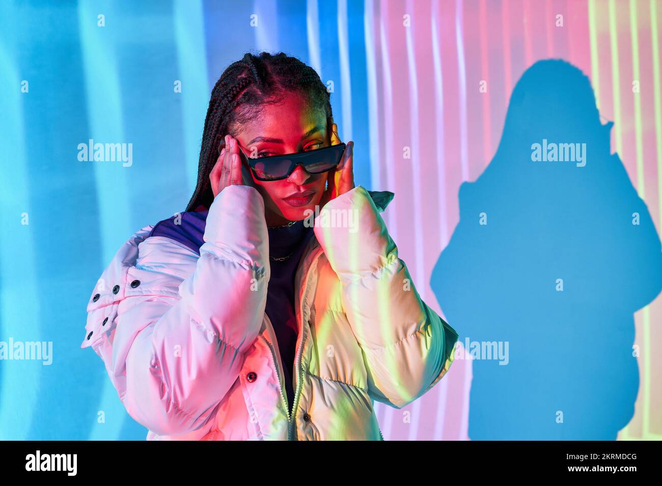 Selbstsichere junge afroamerikanische Millennials mit langen dunklen Zöpfen in warmer Pufferjacke, die selbstbewusst wegblickt und sich trendig anpasst Stockfoto