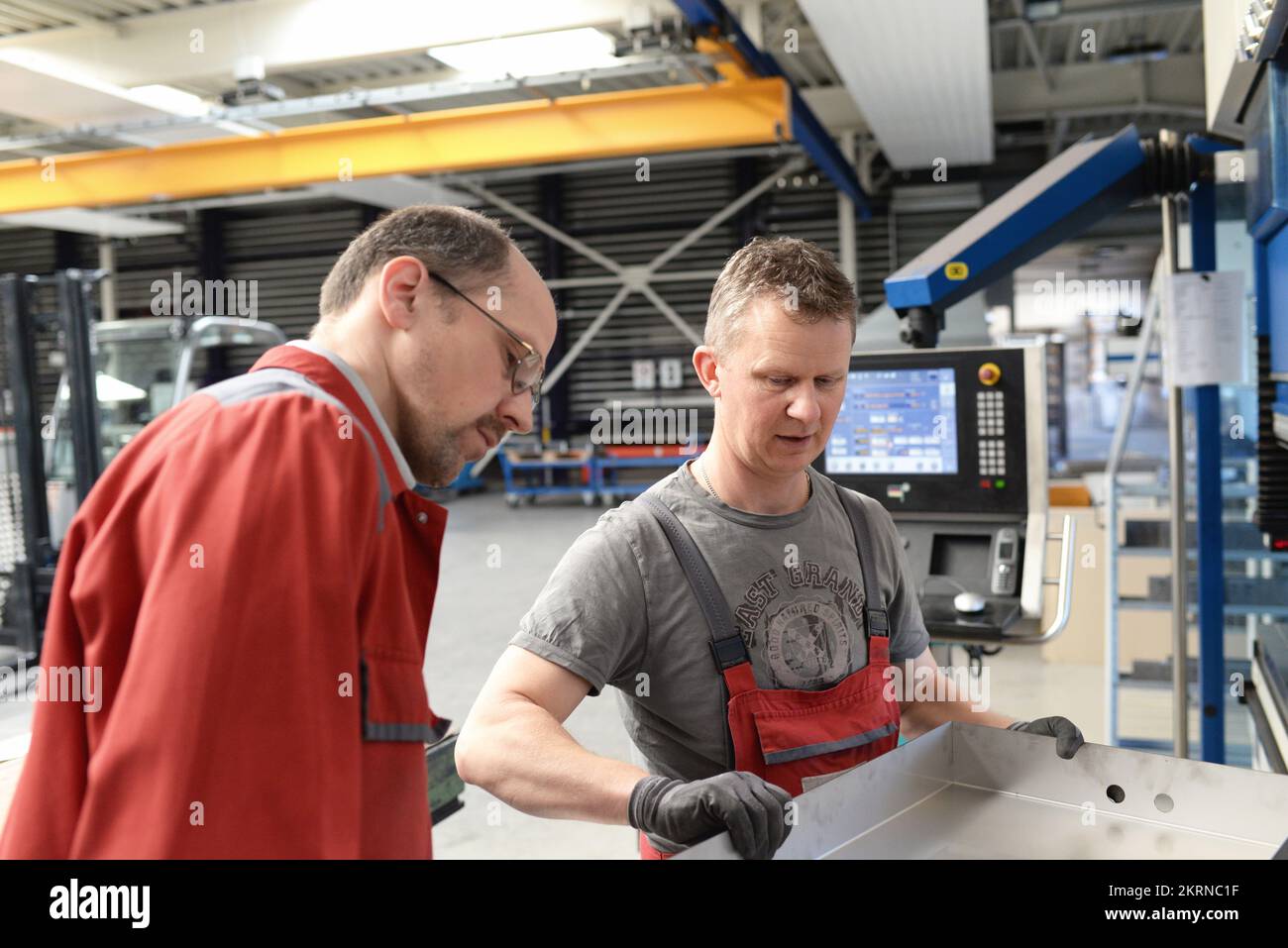 Teamarbeit in der Metallindustrie - zwei Arbeiter und Ingenieure sprechen über die Arbeit in einem Metallbauunternehmen Stockfoto