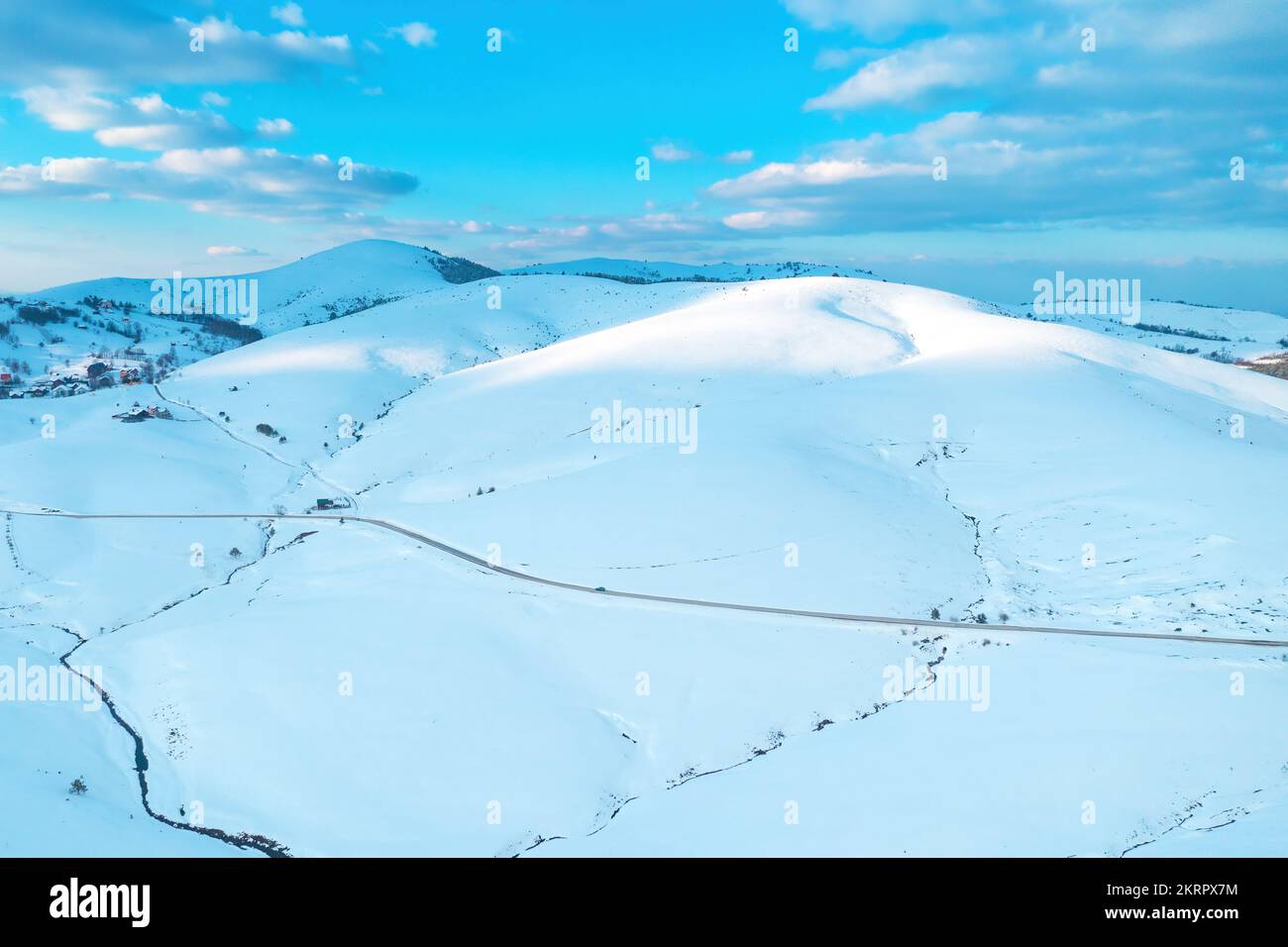Schneebedeckte Hügelspitze, beleuchtet von der untergehenden Sonne bei Sonnenuntergang im Winter in Zlatibor, Serbien. Luftaufnahme von Drohne pov. Stockfoto