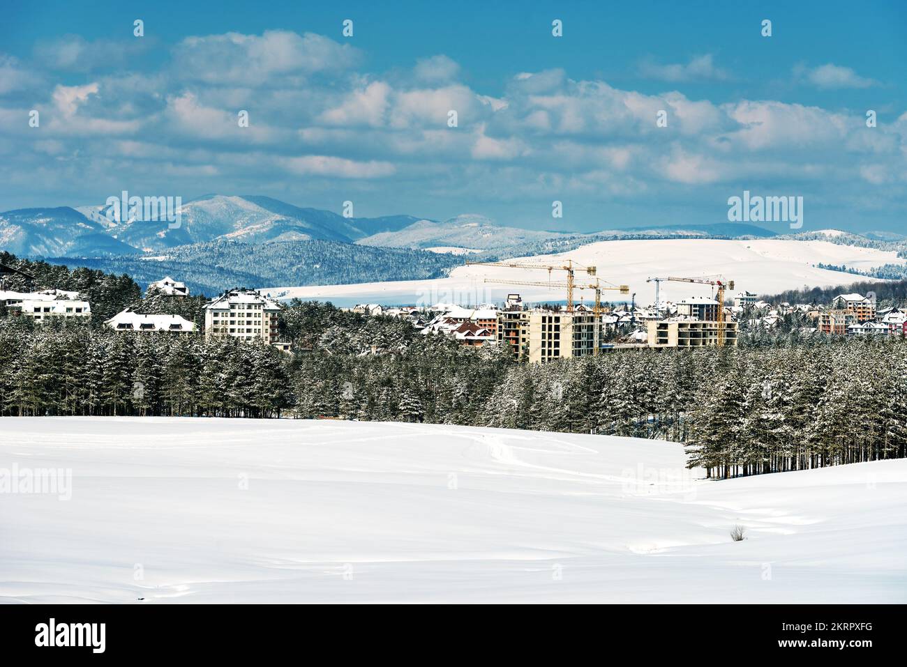 Bauindustrie Wohnung und Wohnungsbau in Zlatibor in der Wintersaison unter Schnee, Gebäude und Kraniche übernehmen die Kiefernwälder Land Stockfoto