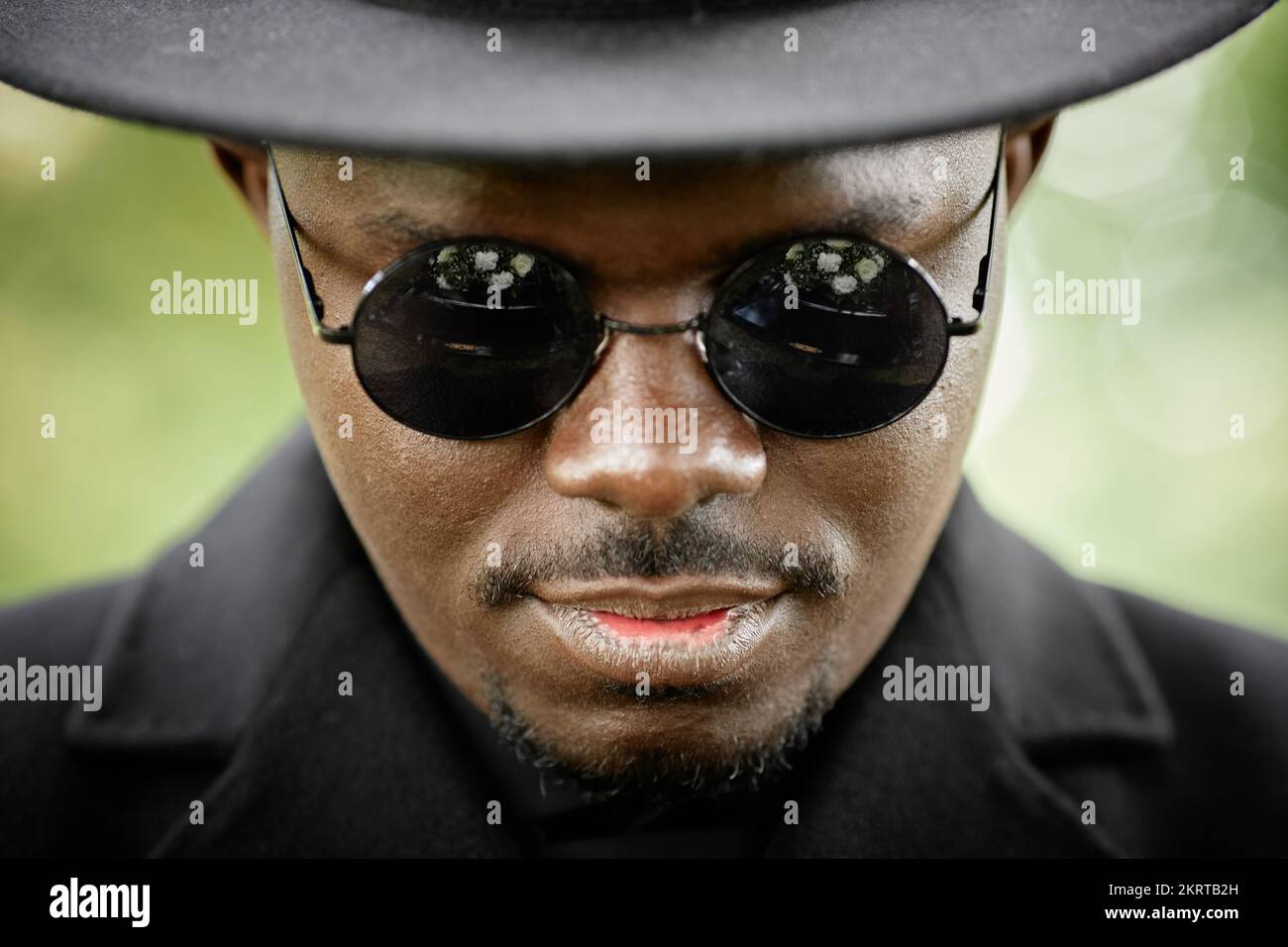 Nahaufnahme eines gutaussehenden afroamerikanischen Mannes mit schwarzem Hut und Sonnenbrille, der dramatisch in die Kamera schaut Stockfoto