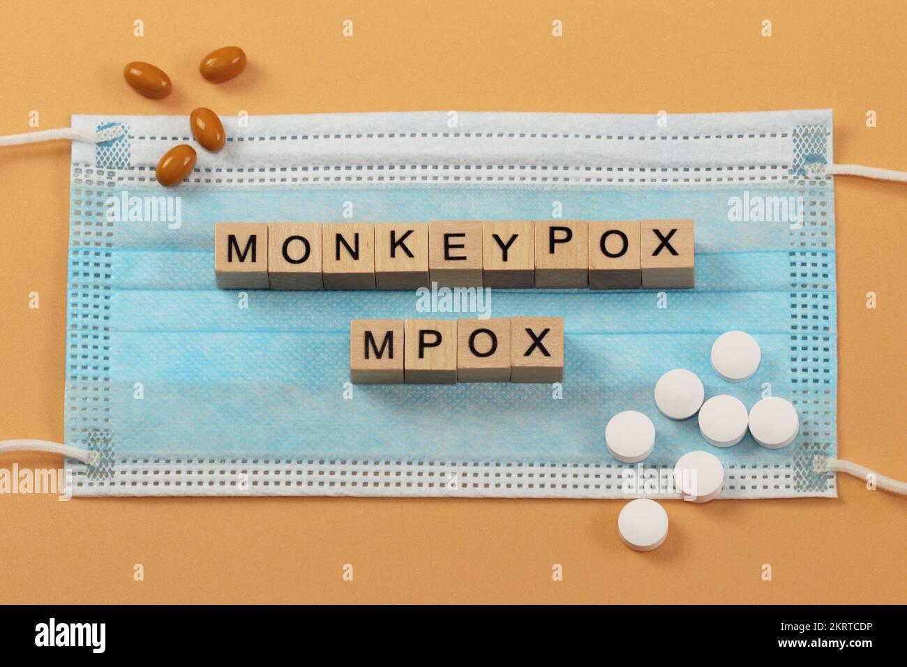 MPOX ist der neue Name für das Affenpockenvirus. Wörter sind mit Holzwürfeln auf einer chirurgischen Gesichtsmaske angelegt. Stockfoto