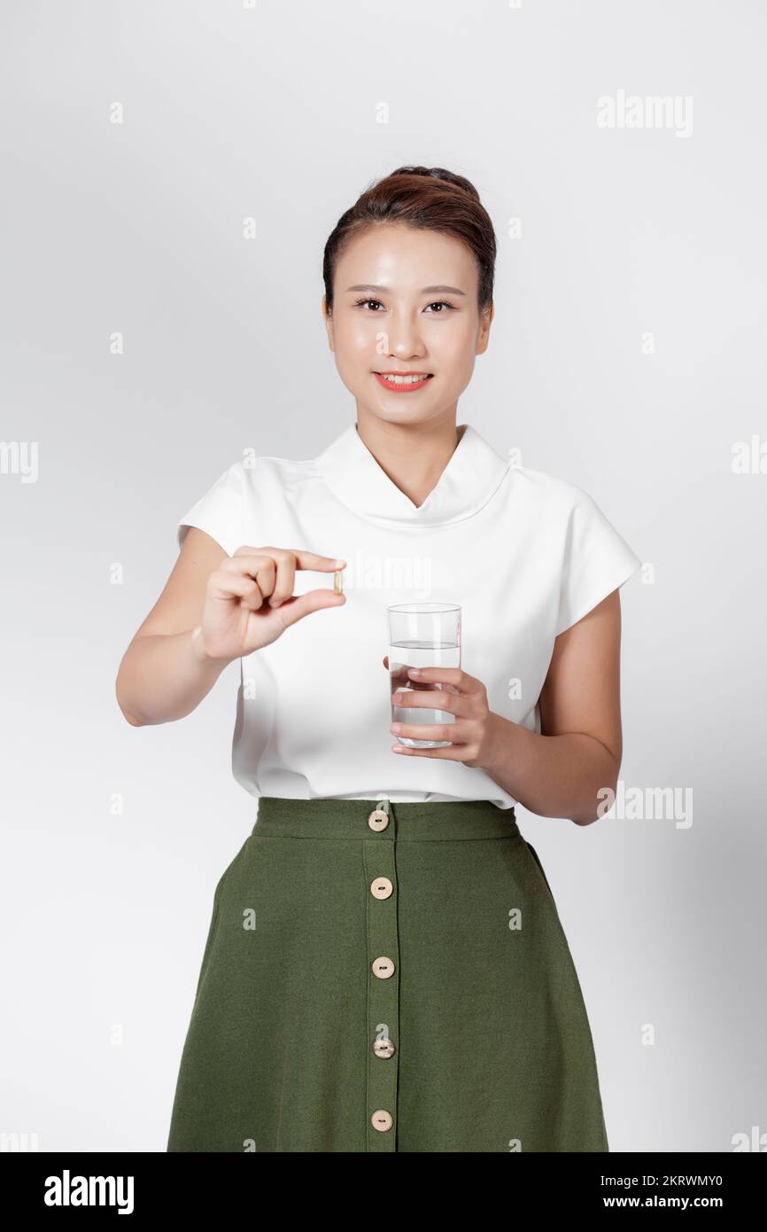 Junge asiatische Frau mit Ergänzungskapsel und einem Glas Wasser Stockfoto