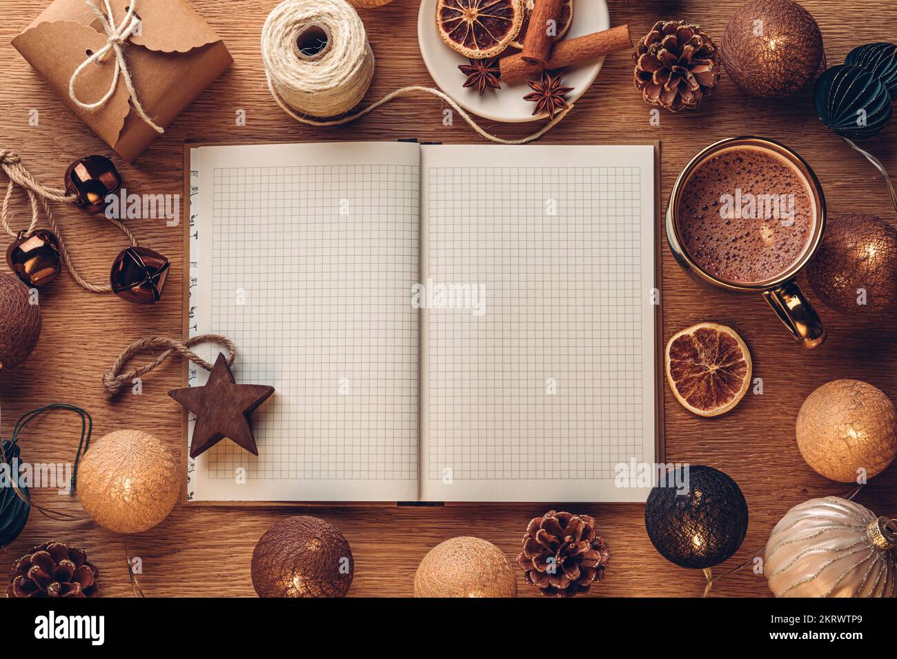Offenes Notizbuch auf Eichenholzhintergrund mit Weihnachtsdekoration und heißer Schokolade in einer Tasse Stockfoto