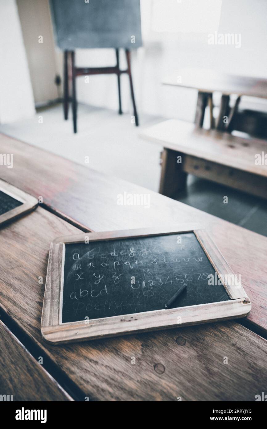 Eine altmodische Kinderschiefertafel mit Schreibstift in einem Schulzimmer. Stockfoto