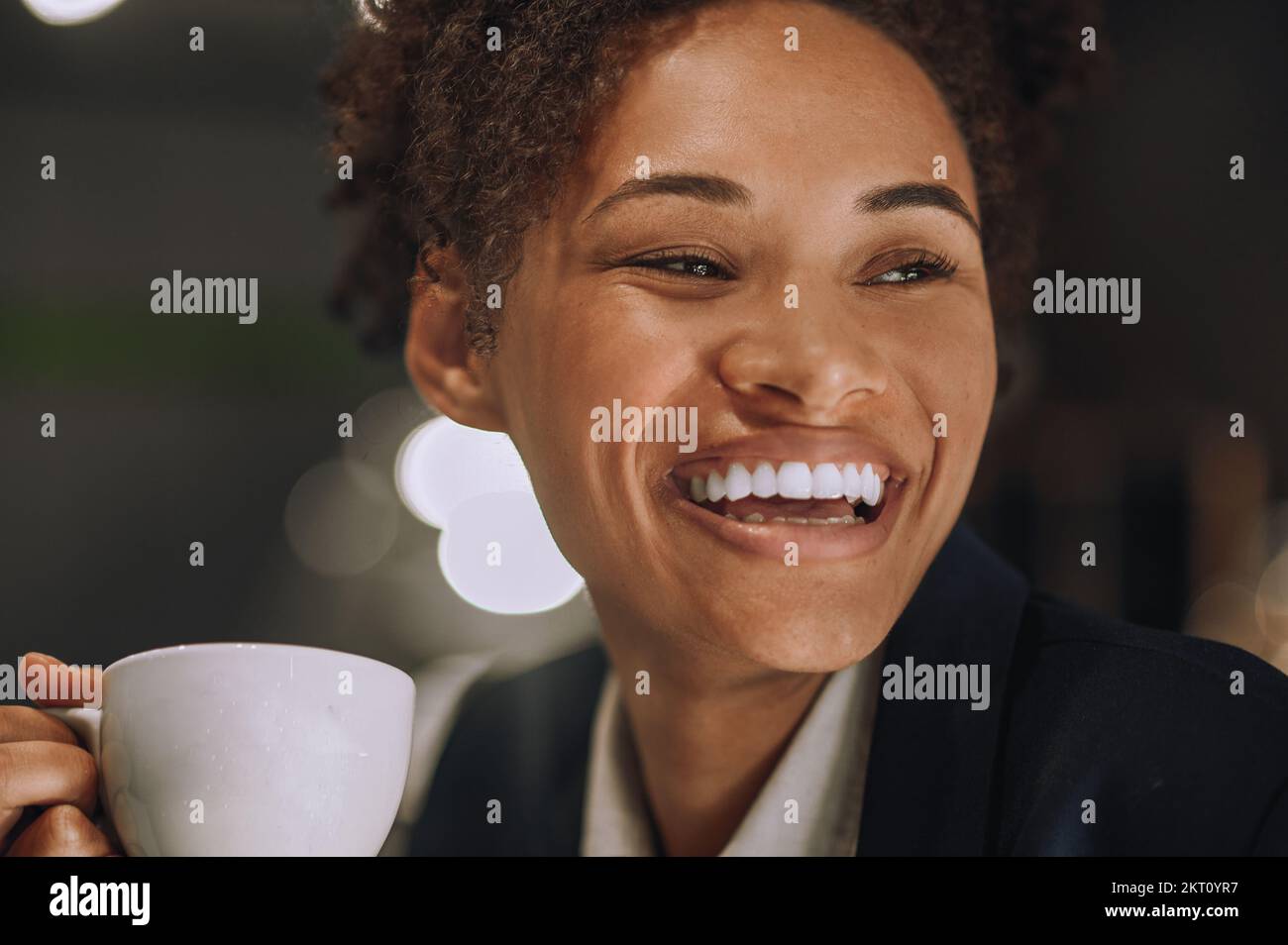 Eine Frau mit einem zahnigen Lächeln und einer Tasse Kaffee Stockfoto