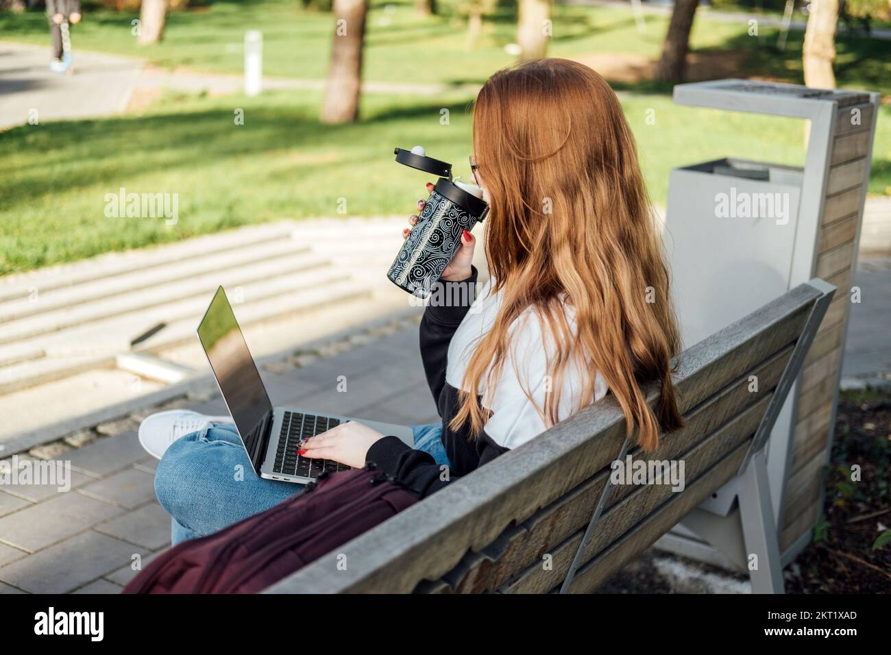 Psychische Gesundheit. Work-Life-Balance, Online-Job oder Ausbildung. Rothaarige Frau, die draußen an einem Laptop tippt. Freiberufler, Studentenmädchen sitzt drauf Stockfoto