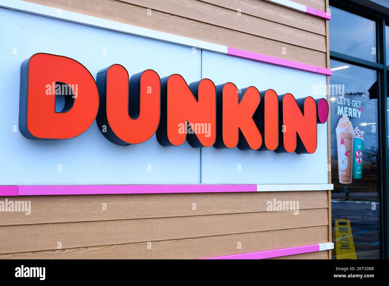 ELLENBURG, NEW YORK, USA - 19. NOVEMBER 2022: An einem Dunkin’ Donuts loc werden Feiertagsgetränke neben einem Schild mit der Wortmarke Dunkin’ angepriesen Stockfoto