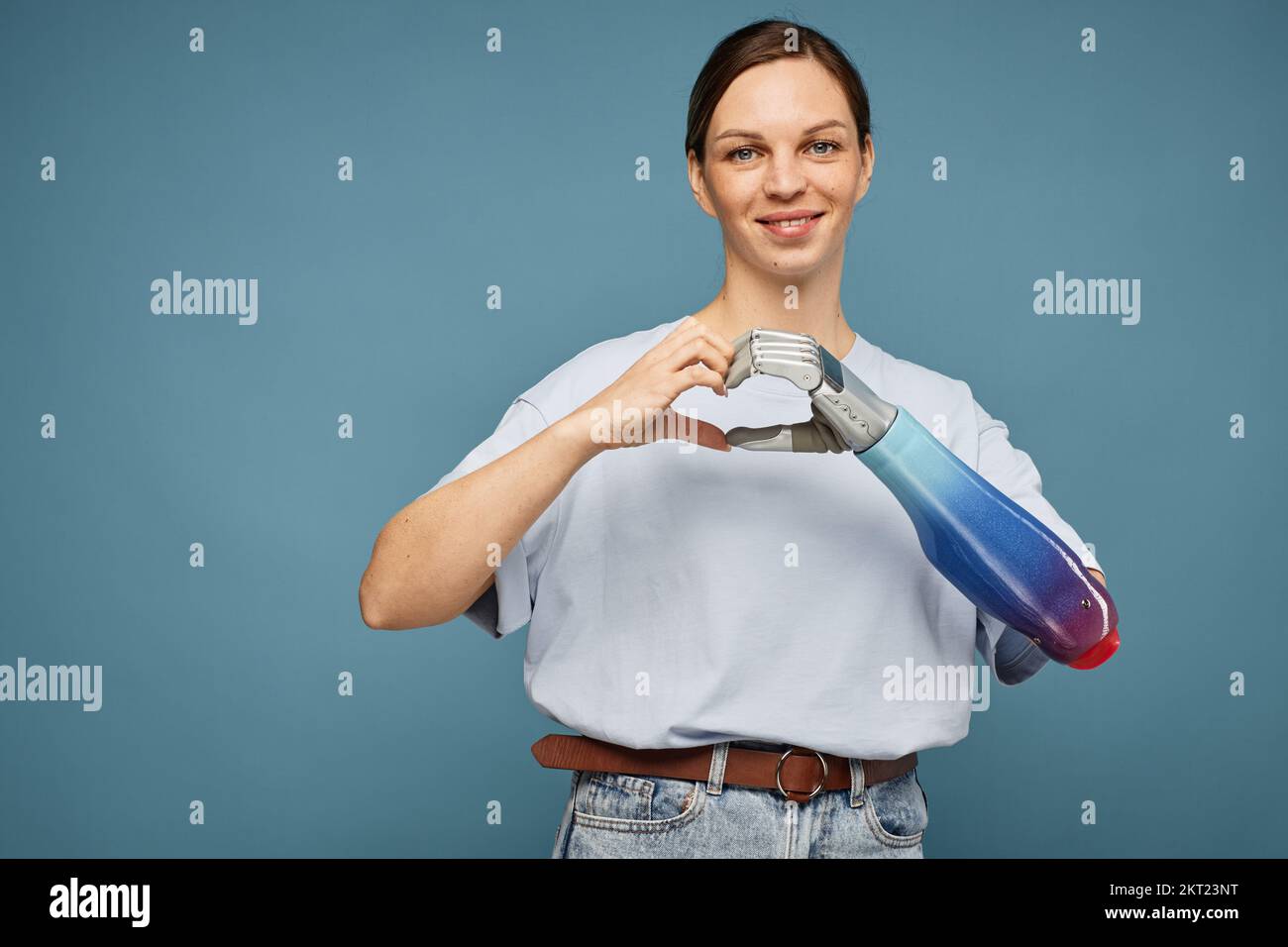 Porträt einer lächelnden Frau mit bionischer Hand, die eine Herzgeste macht Stockfoto