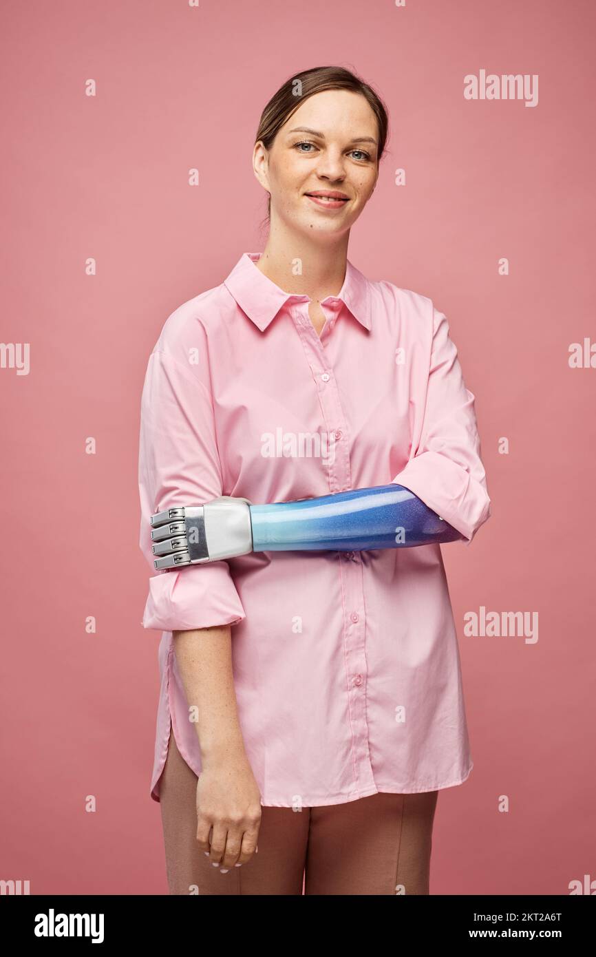 Porträt einer positiven jungen Frau mit bionischer Hand, die vor der Kamera lächelt Stockfoto