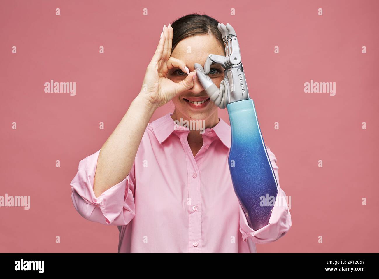 Porträt einer glücklichen, aufgeregten jungen Frau, die Ferngläser mit bionischer Hand macht Stockfoto