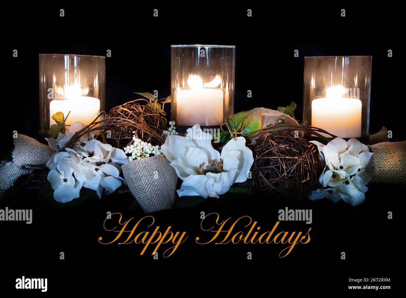 Weihnachtskerzen-Arrangement auf Magnolia-Weinrebe-Herzstück mit Leinenband und „Happy Holidays“-Text. Stockfoto