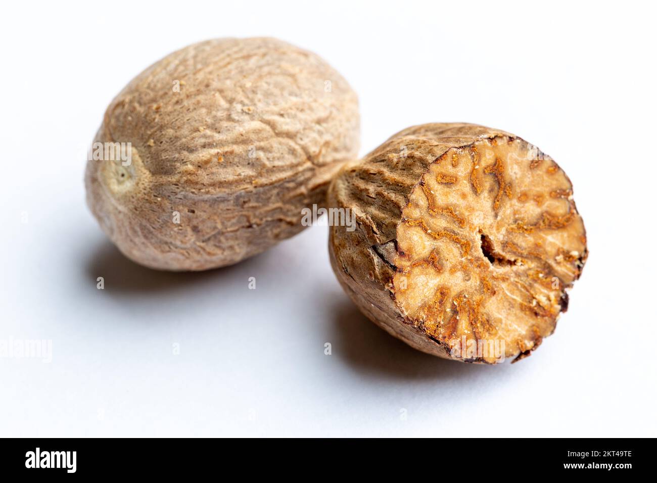 Eine ganze Muskatnuss neben einer halben Muskatnuss Stockfoto