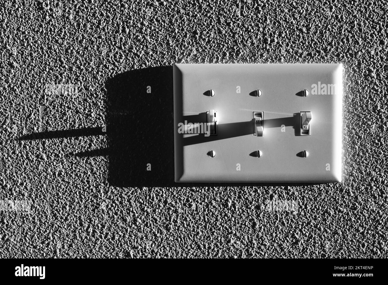 Lichtschalter für mehrere Lichter mit langen dunklen Schatten an der Wand Stockfoto