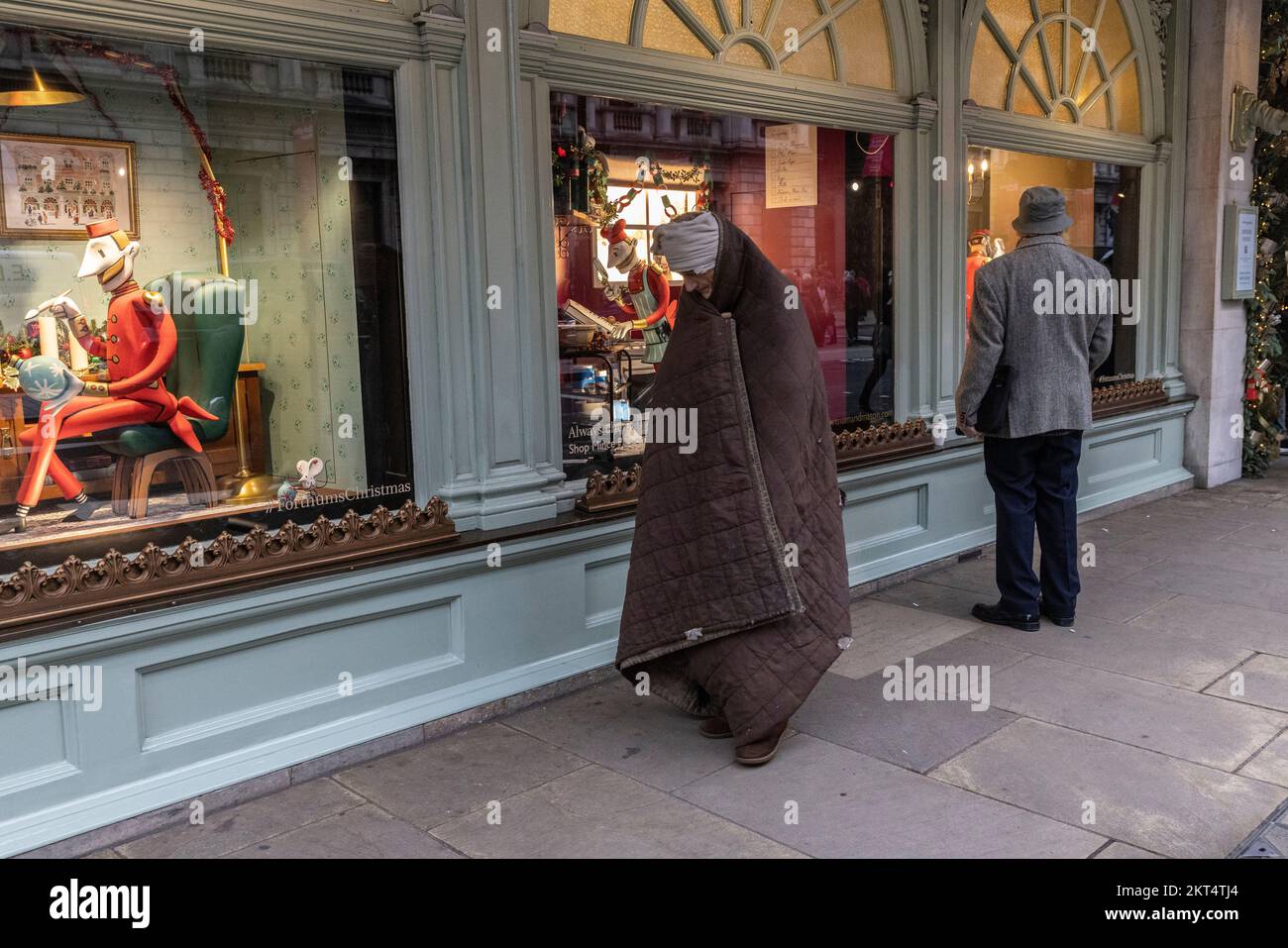Homeless vor Fortnum & Mason in London bei The Fortnum's Christmas Windows während der Weihnachtszeit bis Weihnachten 2022. Stockfoto Homeless vor Fortnum & Mason in London bei The Fortnum's Christmas Windows während der Weihnachtszeit bis Weihnachten 2022. Stockfoto