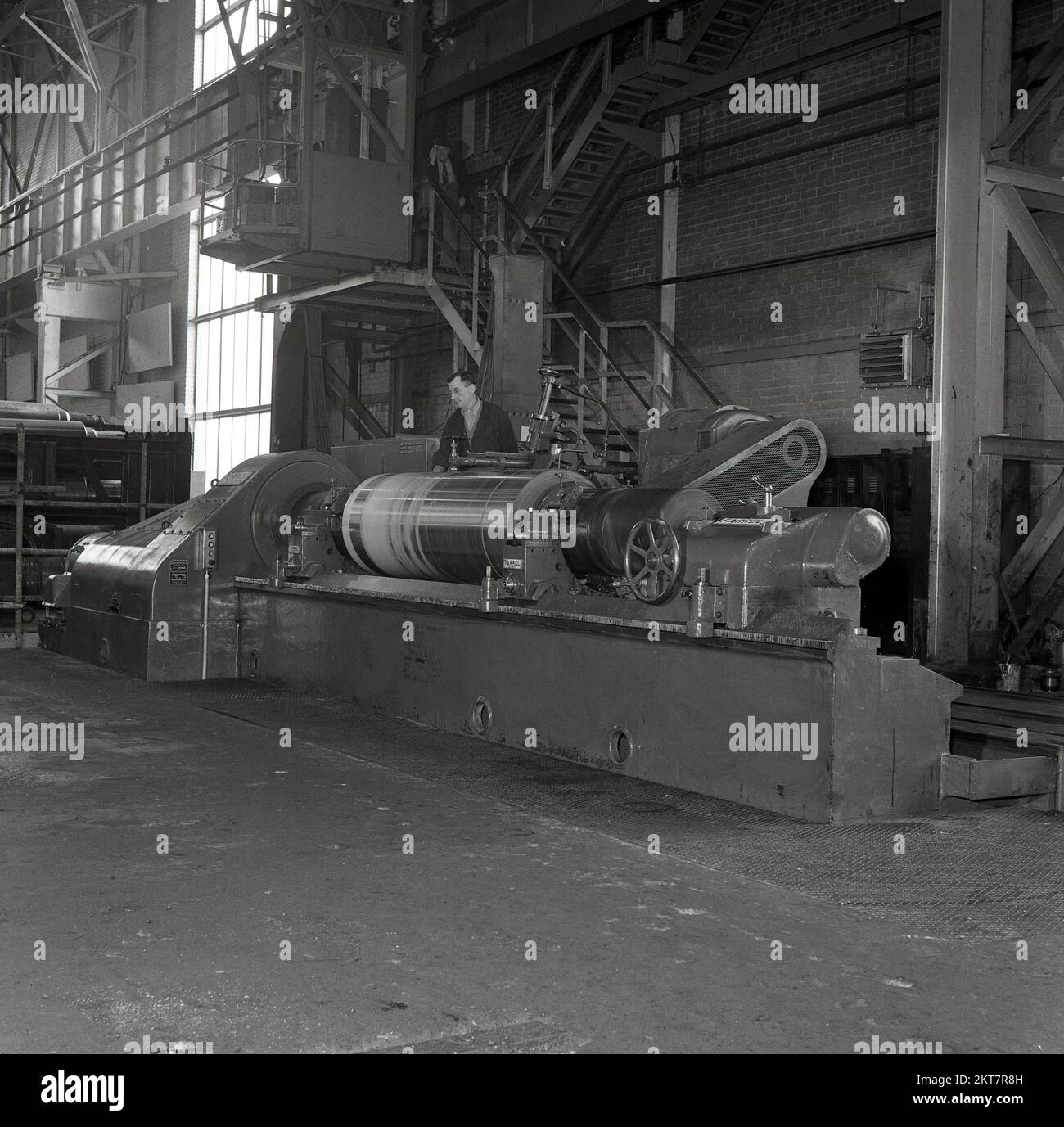 1950er, historisch, Stahlarbeiter, ein Mitarbeiter an einer Schneidemaschine, die Bleche aus Stahl herstellen, bei den Abbey Works, Port Talbot, South Wales, Großbritannien, Sitz der Steel Company of Wales Ltd, zu dieser Zeit der größte Stahlherstellungsstandort in Europa. Der Arbeiter verwendet eine Maschine der Farrel Co, einem Unternehmen, das 1848 in Ansonia, Connecticut, USA, gegründet wurde, von Almon Farrel, das Holzbearbeitungsmaschinen herstellt. Stockfoto