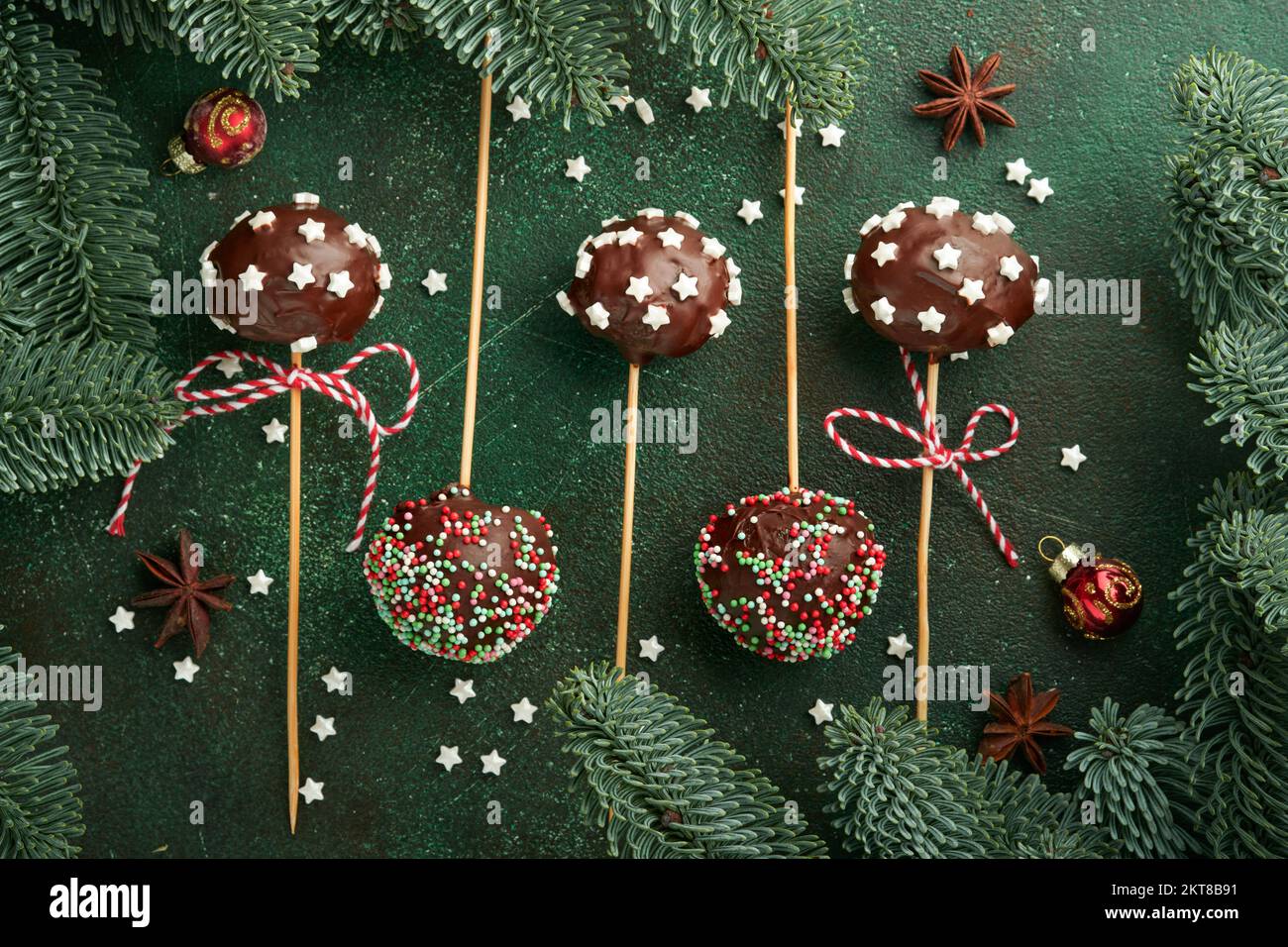 Heirate Weihnachten, süße Kuchenpopps. Weihnachtsdessert runde Brownie-Kuchen mit Sternen auf dunkelgrünem Hintergrund. Weihnachtsessen Dessertkonzept Stockfoto