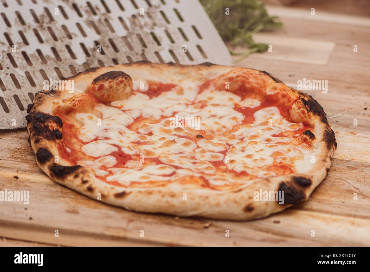 Serviert heiße Pizza Margherita mit Tomatensoße und Mozzarella mit einer Schaufel auf einem Holzbrett, mit Rauch Stockfoto