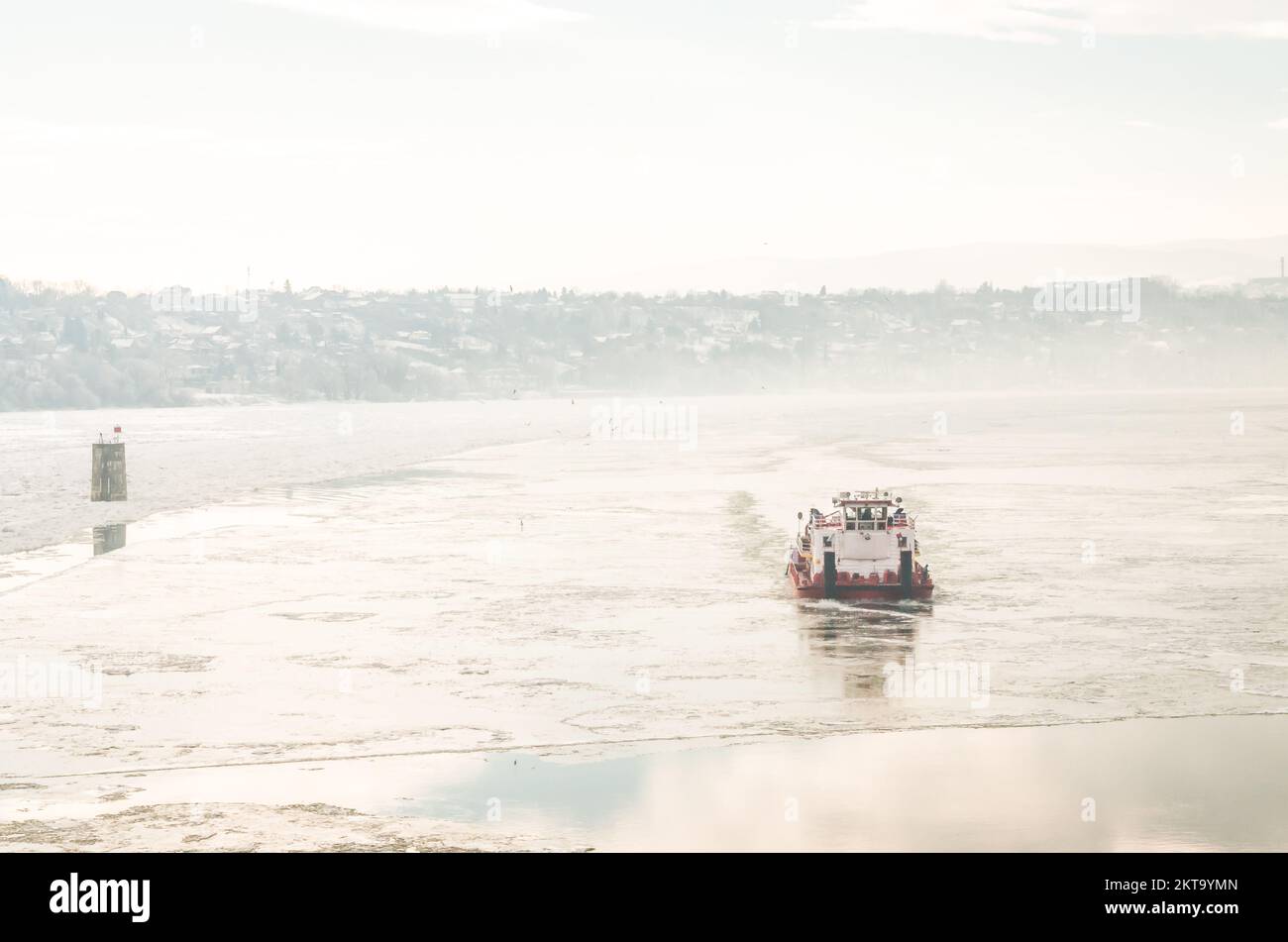 Die Donau ist mit Schnee und Eis bedeckt. Ein Eisbrecherschiff in der gefrorenen und schneebedeckten Donau unterhalb der Festung Petrovaradin Stockfoto