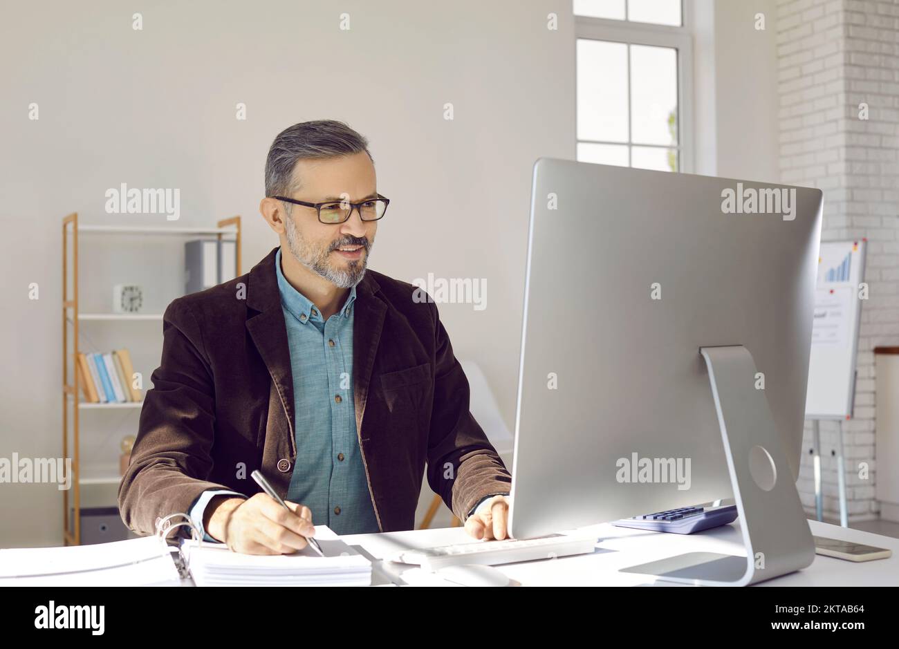 Erfahrener Geschäftsmann oder Finanzbuchhalter, der im Büro an einem Desktop-Computer arbeitet Stockfoto