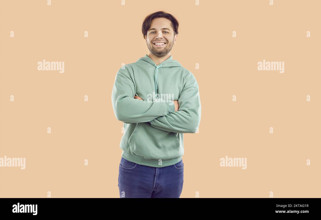 Porträt eines fröhlichen, lächelnden brünetten Mannes in Minzpullover und Jeans auf beigefarbenem Hintergrund, der auf die Kamera schaut. Stockfoto Porträt eines fröhlichen, lächelnden brünetten Mannes in Minzpullover und Jeans auf beigefarbenem Hintergrund, der auf die Kamera schaut. Stockfoto