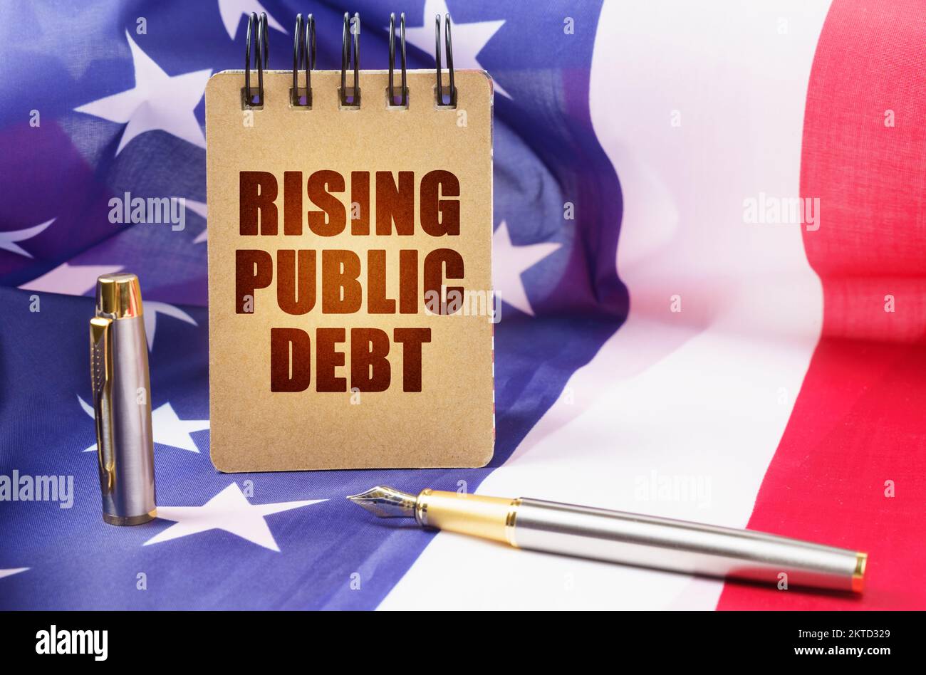 Geschäftskonzept. Vor dem Hintergrund der amerikanischen Flagge ist ein Notizblock mit der Inschrift "steigende Staatsverschuldung" Stockfoto