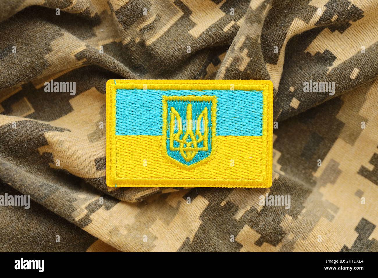 Pixeliges digitales Tarnmaterial mit ukrainischer Flagge und Wappen auf Chevron in Blau und Gelb. Attribute der ukrainischen Soldatenuniform Stockfoto