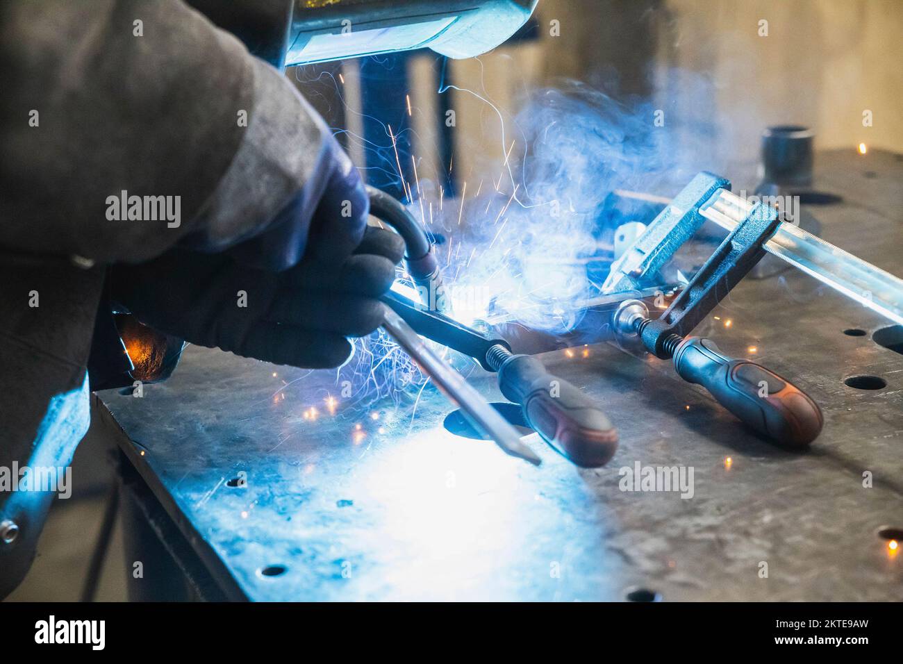 Halbautomatisches Schweißen mit Funken und Rauch im Werk Stockfoto