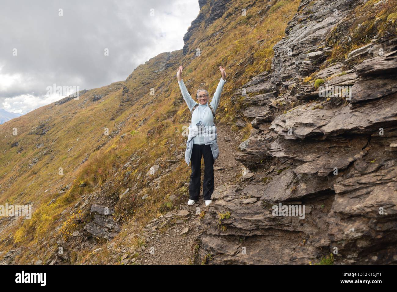 Eine Frau mit guter Laune bewegt sich auf einem felsigen Pfad, den österreichischen Alpen. Hochwertiges Foto Stockfoto