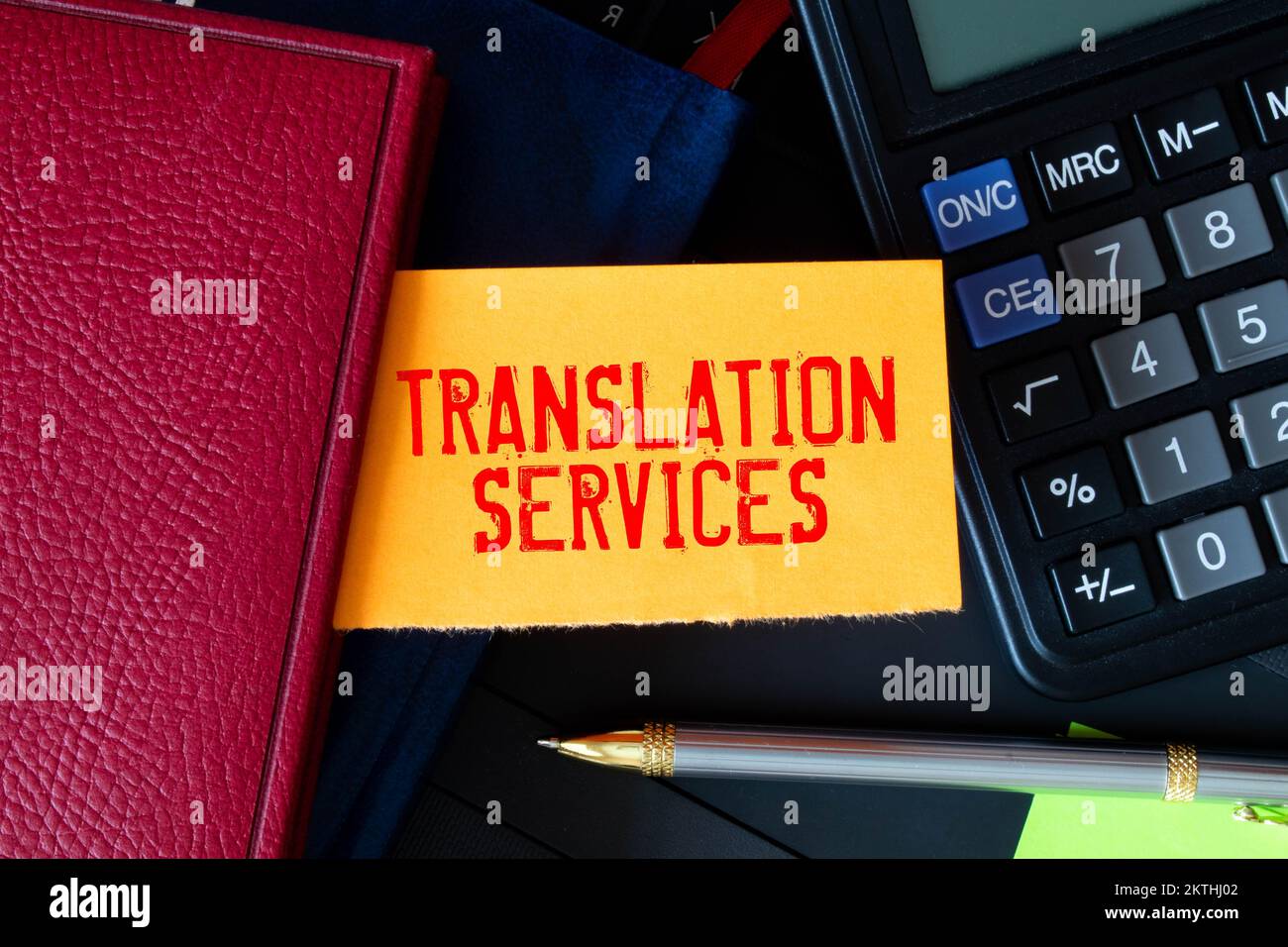 Auf hellem Hintergrund, goldgerahmte Gläser, eine Blume im Topf, ein grünes Notizbuch, ein roter Stift und ein braunes Notizbuch mit den TEXTÜBERSETZUNGSDIENSTEN. Bu Stockfoto